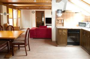 eine Küche und ein Esszimmer mit einem Tisch und einem roten Sofa in der Unterkunft Rössli Holiday Apartment in Interlaken