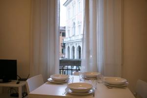 una mesa con platos y gafas blancos y una ventana en Pampurio en Pisa