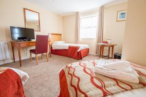 a hotel room with two beds and a desk with a computer at The Black Horse Inn in Louth