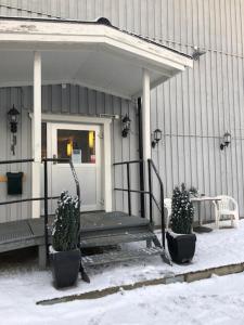 a porch of a house with two potted plants at Mälarö Hotell in Ekerö