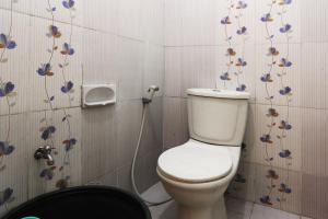 a bathroom with a toilet with flowers on the wall at Ombey Guest House in Bogor