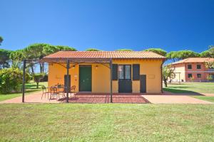 a small yellow house with a table in a yard at La Fattoria di Tirrenia in Tirrenia