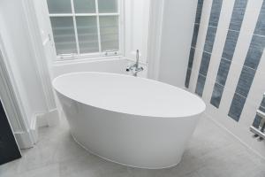a white bath tub in a bathroom with a window at The Rutland Hotel & Apartments in Edinburgh