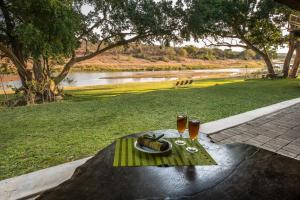 een tafel met een bord eten en twee glazen wijn bij Maninghi Lodge in Balule Game Reserve