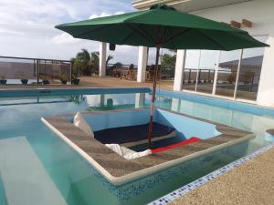 a lounge chair with an umbrella in a swimming pool at Seaview Mansion Dalaguete Apartment 3 in Dalaguete