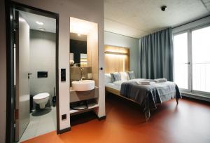 a bedroom with a bed and a sink and a bathroom at Hotel Rossi in Berlin