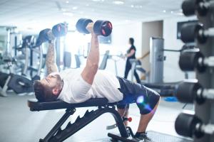 a man laying on a bench in a gym lifting weights at Mercure Newcastle George Washington Hotel Golf & Spa in Newcastle upon Tyne