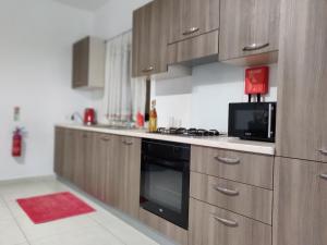 a kitchen with wooden cabinets and a stove top oven at Spacious two bedroom apartment within 5 minutes walk from St Thomas Bay in Marsascala in Tas-Santi