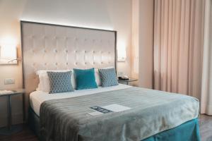 um quarto com uma cama grande e almofadas azuis em Gran Hotel Havana 4Sup by Escampa Hotels em Barcelona