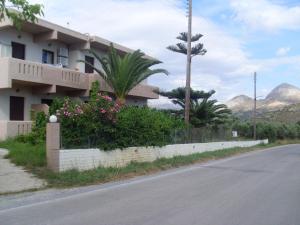 a house on the side of a road with mountains in the background at Elena Rooms in Plakias