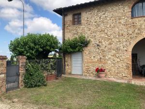 uma casa de tijolos com uma porta branca e uma cerca em Casa di Romano, Al Tramonto em Marcialla