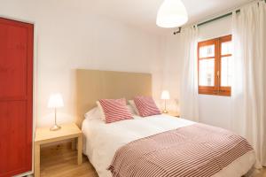 a white bedroom with a bed with two pillows at Mundo Nuevo: Acogedor Apartamento en el Centro in Málaga