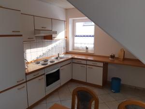 eine Küche mit weißen Schränken, einem Waschbecken und einem Fenster in der Unterkunft Ferienwohnungen Sonnenpfad in Schmallenberg