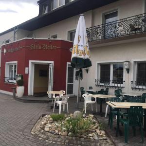 a patio with tables and chairs and an umbrella at Gasthaus "Zur alten Dorfschmiede" in Metterich