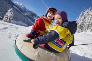 a man and a woman riding on a snowboard at Almhof Family und Wellness Resort in Gerlos