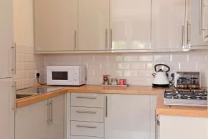 a kitchen with white cabinets and a white microwave at Jevington Gardens in Eastbourne
