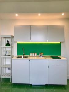 uma cozinha com armários brancos e uma parede verde em Sorrento Olive Tree Garden em Sorrento