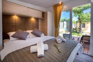 a bedroom with a large bed and a balcony at Valamar Camping Ježevac in Krk