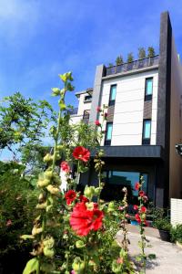 un edificio con flores rojas delante de él en Early Summer, en Luodong