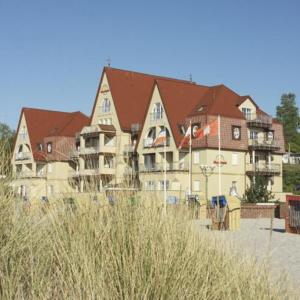 a large building with brown roofs in front of a beach at Strandhotel Grömitz in Grömitz