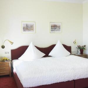 a bedroom with a large bed with white sheets at Strandhotel Grömitz in Grömitz