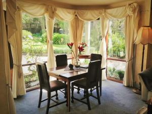 ein Esszimmer mit einem Tisch und Stühlen vor einem Fenster in der Unterkunft Bindley House B&B Cottage in Kilmore