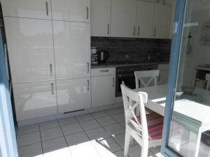 ツィノヴィッツにあるAppartement Residenz Bellevue Usedom 52 DSL WLAN kostenlosの白いキャビネット、テーブルと椅子付きのキッチンが備わります。