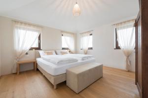 a white bedroom with a large white bed and windows at Untermargarethenhof in Lana