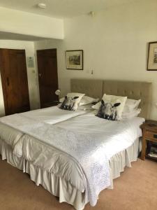 a large white bed with two dogs on the pillows at Holmeshead Farm in Ambleside