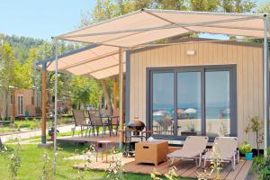 a house with an umbrella and chairs and a grill at Armenistis Camping & Bungalows in Sarti