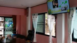 a living room with a tv and windows with curtains at Ocean View Resort - Koh Sichang in Ko Si Chang