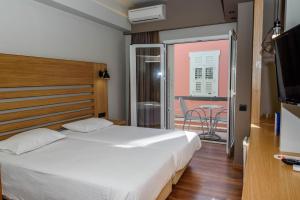a bedroom with a bed and a balcony with a table at Agamemnon Hotel in Nafplio
