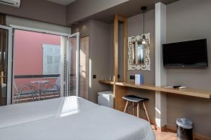 a bedroom with a bed and a television and a table at Agamemnon Hotel in Nafplio