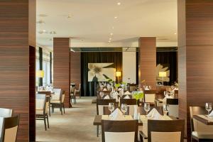 a dining room with tables and chairs in a restaurant at Sunday Hotel Leipzig-Halle in Landsberg OT Peißen