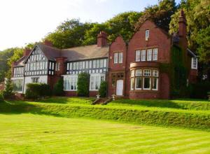 a large red brick house on a green lawn at Brass Castle Country House Accommodation in Middlesbrough