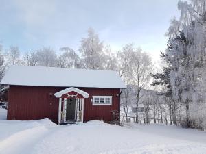 un granero rojo con nieve encima en Backens Fjällboende, en Tännäs