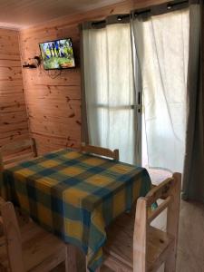 comedor con mesa, sillas y TV en Cabaña Gabon, en Barra del Chuy