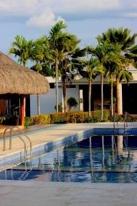 a swimming pool with palm trees and a building at Hotel Emerawaa in Ríohacha