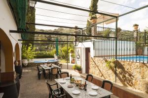 eine Terrasse mit Tischen und Stühlen und einem Pool in der Unterkunft Cortijo La Algallumbilla in Carcabuey