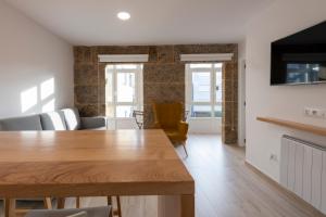cocina y sala de estar con mesa de madera y sillas en Apartamentos Mar de Fondo Muxia en Muxía