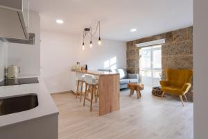 cocina y sala de estar con mesa y sillas en Apartamentos Mar de Fondo Muxia en Muxía