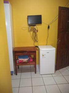 a room with a refrigerator and a television on a wall at Pousada União Tavares in Mateiros