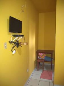 a room with a yellow wall with a television and a chair at Pousada União Tavares in Mateiros
