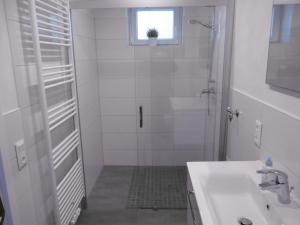 ein weißes Bad mit einer Dusche und einem Waschbecken in der Unterkunft Ferienwohnung Wiesenblick nahe Region Celle und Hannover in Buchholz (Aller)