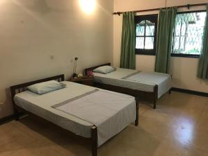 two beds in a room with green curtains at Cinnamon Bungalow in Negombo