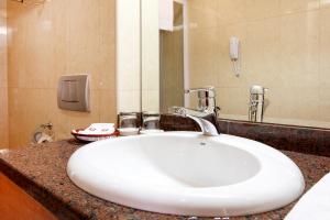 a white sink sitting under a mirror in a bathroom at Hotel Duke Romana in Bucharest