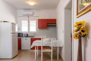 uma cozinha com armários vermelhos e um frigorífico branco em Apartments Beba - peaceful location em Trogir