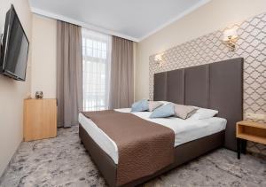 a hotel room with a large bed and a television at Villa Grand Solis in Świnoujście