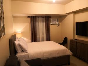 a bedroom with a bed and a flat screen tv at Cagayan de oro condo rentals 21 in Cagayan de Oro