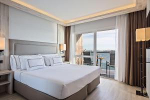 a bedroom with a large white bed and a balcony at Melia Alicante in Alicante